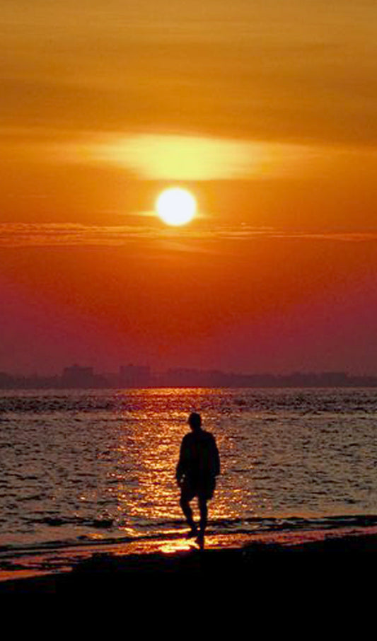 Person Walking on a Beach at Sunset